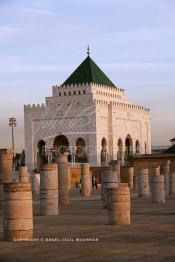 Image du Maroc Professionnelle de  Le tombeau du plus populaire des sultans du Maroc, Mohammed V, père de l’indépendance repose ici dans cette  demeure bâtie en marbre blanc et couronnée par un toit pyramidale orna de tuiles vertes, symbole de la royauté. Sa construction a nécessita une dizaine d’année, au premier plan  les colonnes de l’esplanade de la Mosquée Hassan à Rabat, Jeudi 1er Mars 2007. (Photo / Abdeljalil Bounhar)
